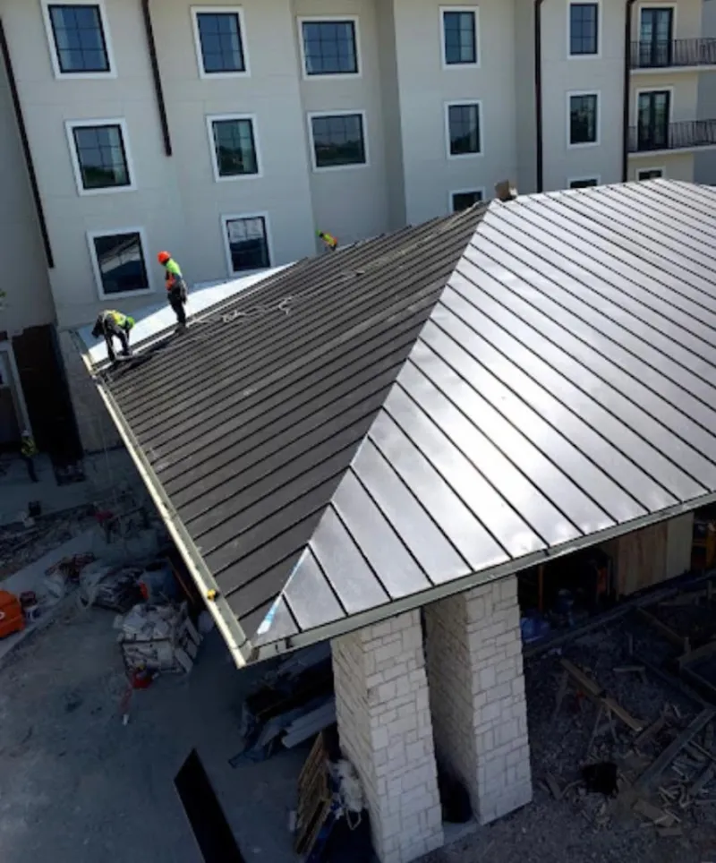 Crew installing standing seam metal roof panels on a commercial project in Crosspointe